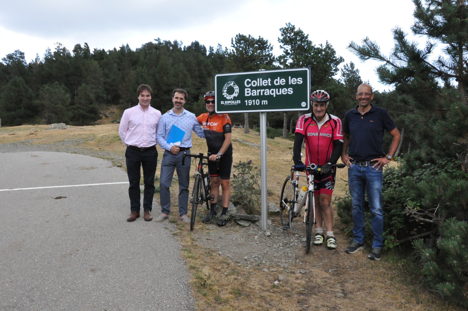 El president, Joaquim Colomer, el conseller Xavier Guitart i alguns ciclistes, al costat del rètol de final de ruta del collet de les Barraques