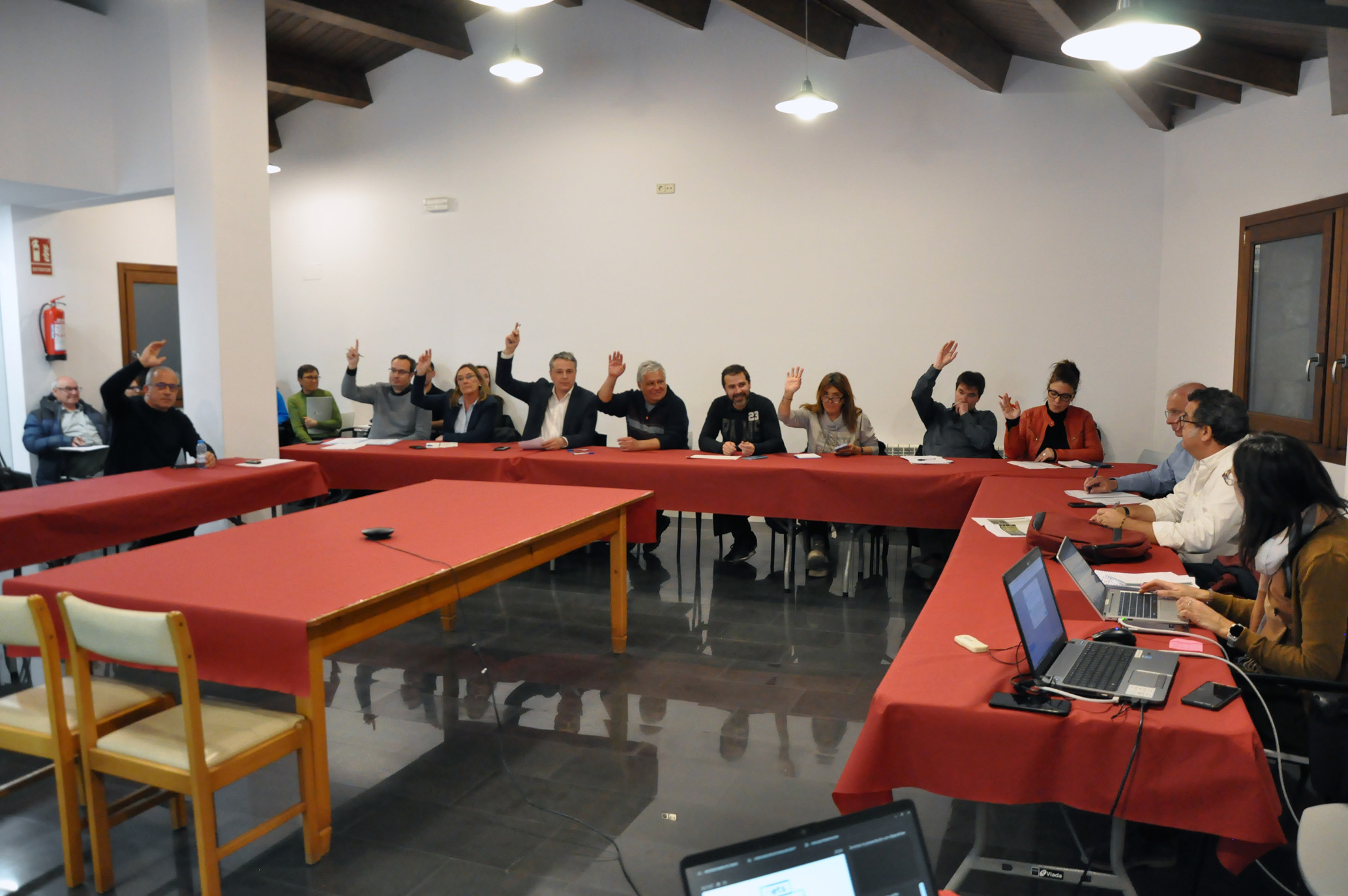 Els batlles presents al Consell d'alcaldes i alcaldesses i alcaldesses del Ripollès del 14 de març de 2023, amb la mà aixecada, durant una votació