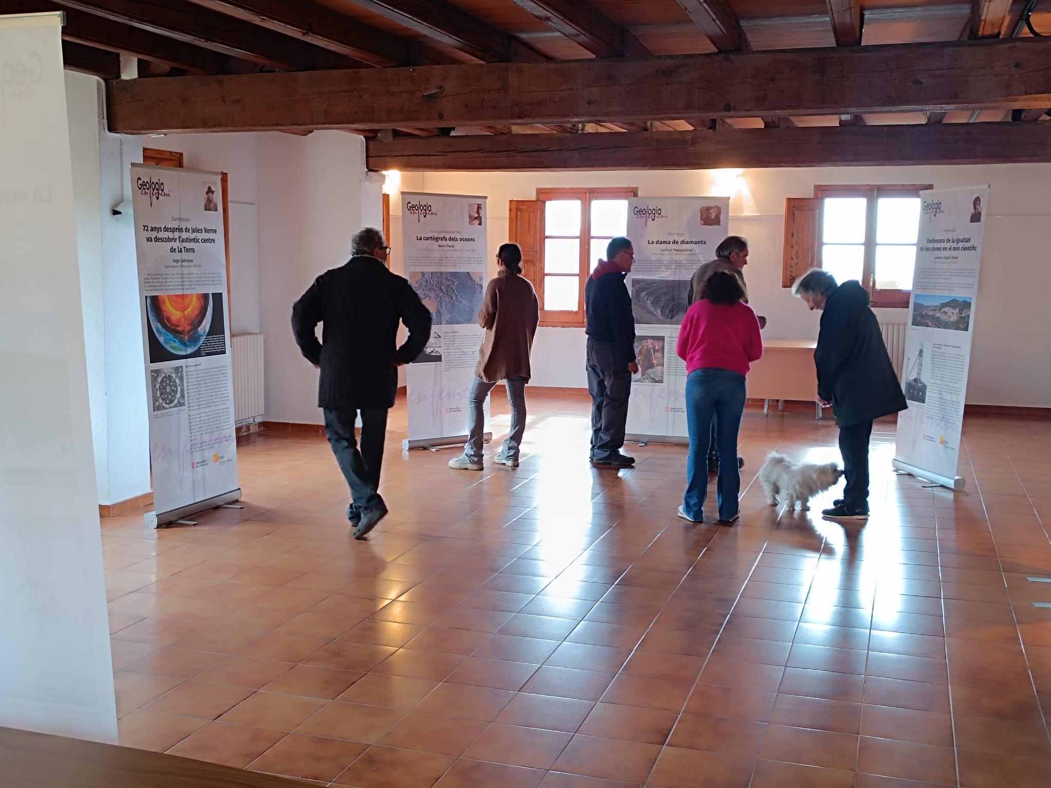 Diverses persones visitant l'exposició "Geografia en femení", a un recinte tancat de Campelles